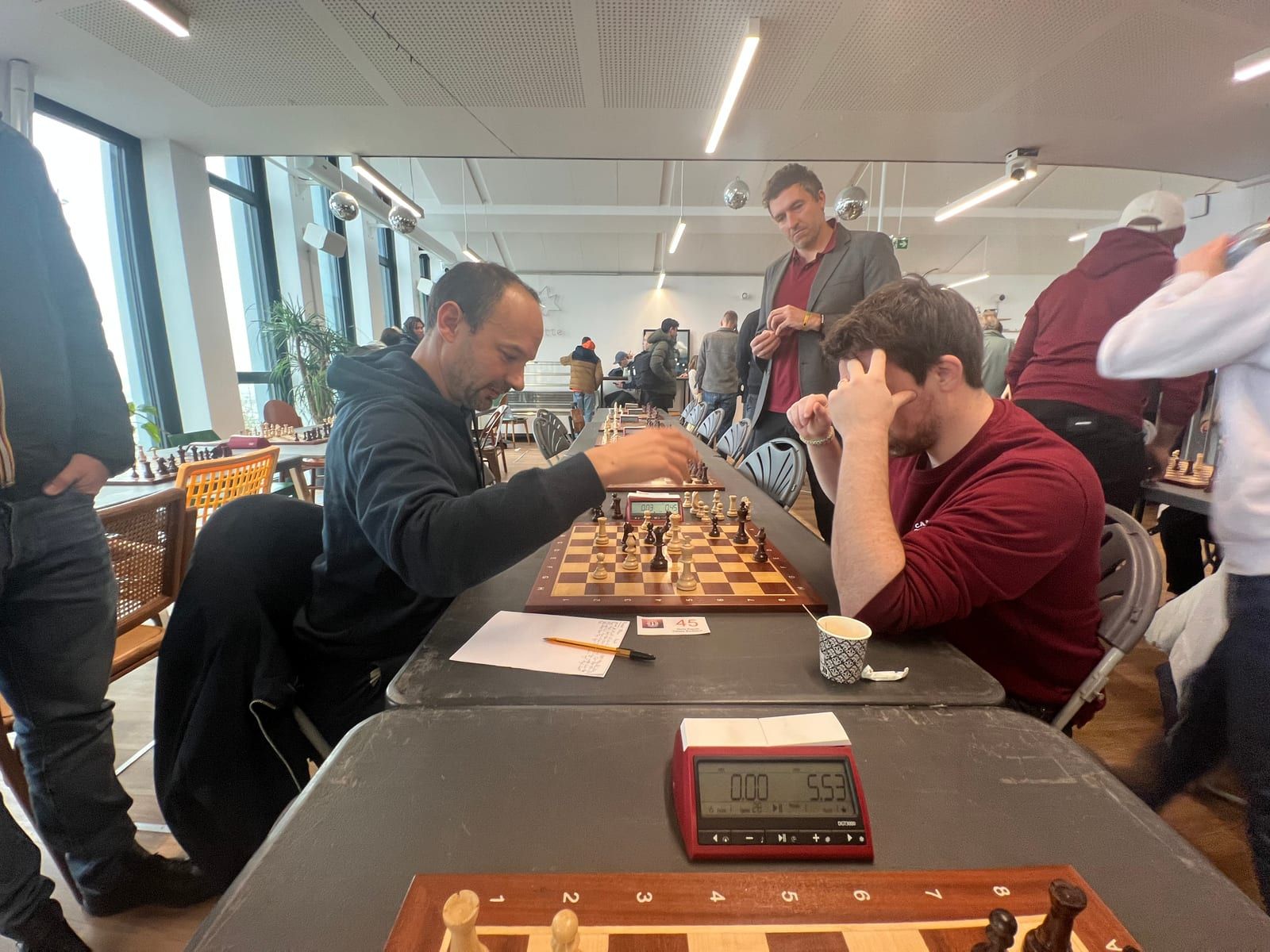 Focused players at an over-the-board chess tournament, clock in the foreground
